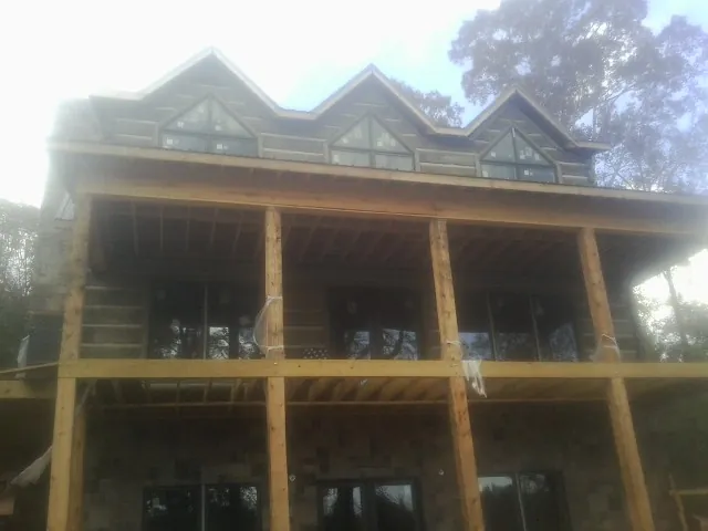 Dormers and porch framing on a large log home under construction — Roof Coating work by our crew in Chatham