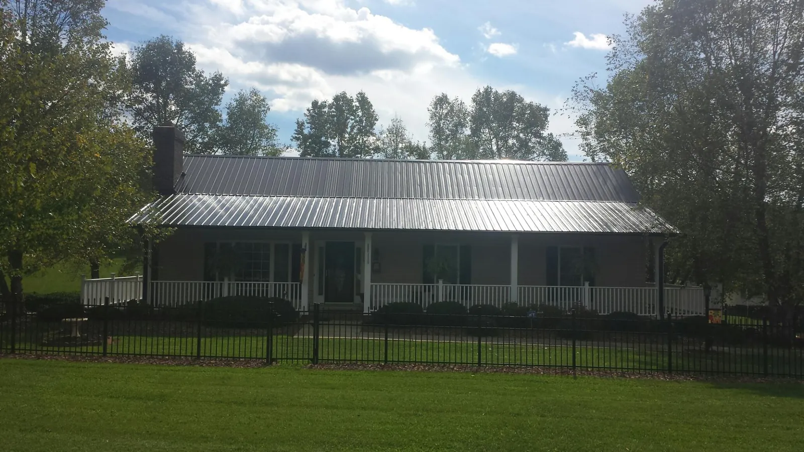 Gray metal roof on a brick ranch with a full width front porch — Gutter Guard Installation work by our crew in Chatham